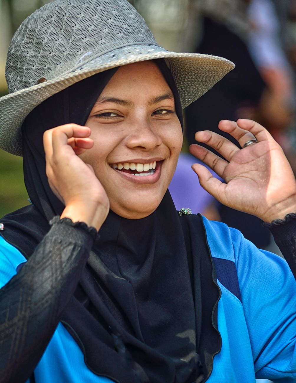 Wanita bertudung tersenyum di luar bangunan pada siang hari
